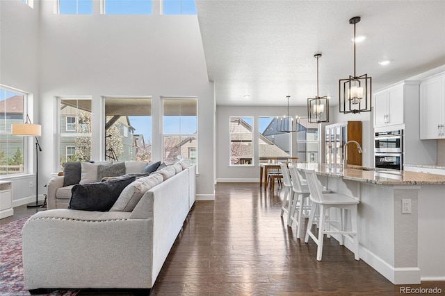 living room with dark wood-style floors, baseboards, and a notable chandelier