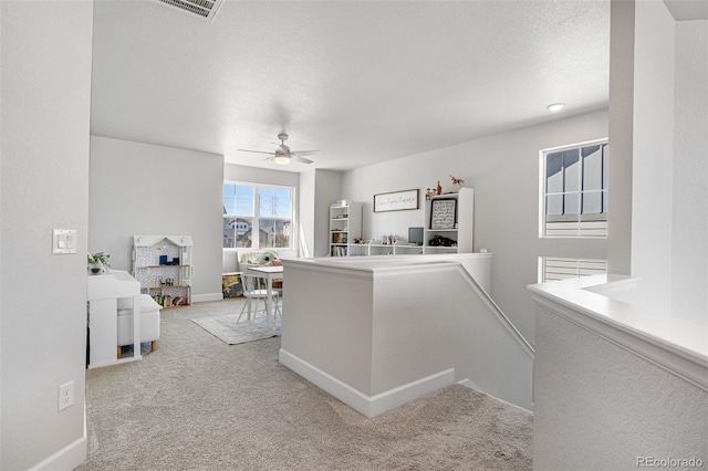 hallway with carpet, baseboards, and an upstairs landing
