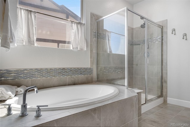 bathroom featuring baseboards, a bath, and a stall shower