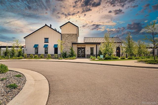 view of front facade with a standing seam roof, stone siding, and board and batten siding