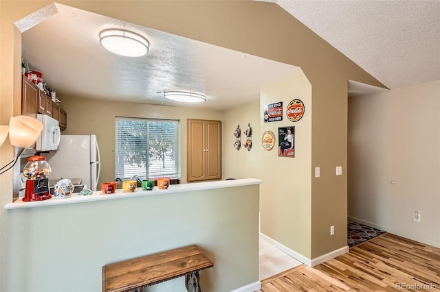 17948 E Colgate Pl, Aurora, CO 80013 - kitchen with white appliances, light wood-type flooring, a peninsula, a kitchen bar, and a textured ceiling