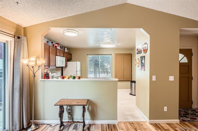 17948 E Colgate Pl, Aurora, CO 80013 - kitchen with white appliances, light wood-type flooring, arched walkways, a peninsula, and lofted ceiling