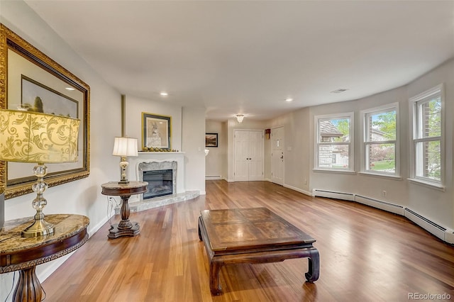 living room with a high end fireplace, wood-type flooring, and baseboard heating