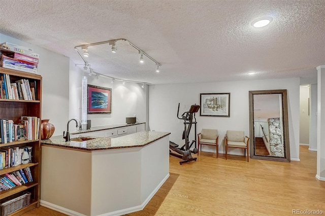 kitchen featuring a textured ceiling, sink, and light wood-type flooring