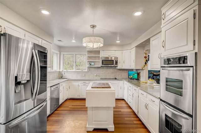 kitchen featuring white cabinets, appliances with stainless steel finishes, a center island, and hardwood / wood-style flooring