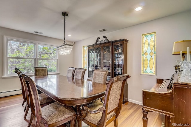 dining room featuring light hardwood / wood-style flooring, a chandelier, and a baseboard heating unit