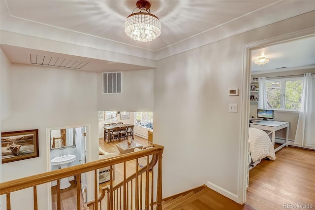 hallway with a notable chandelier and light hardwood / wood-style floors