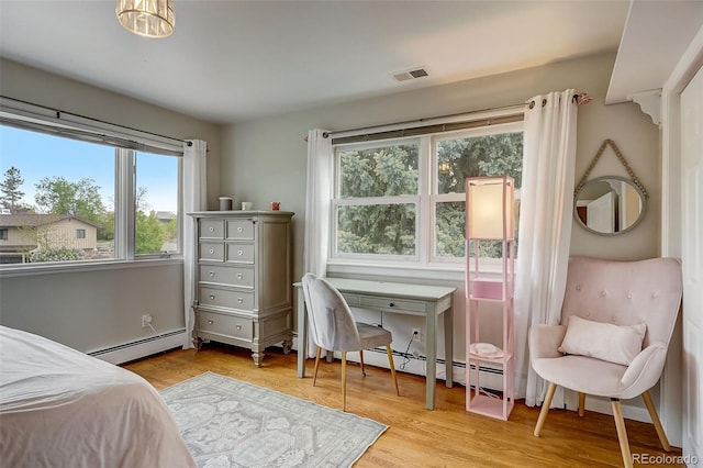 bedroom with a baseboard heating unit and light hardwood / wood-style flooring