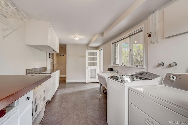 clothes washing area featuring dark tile floors, cabinets, sink, and washer and dryer