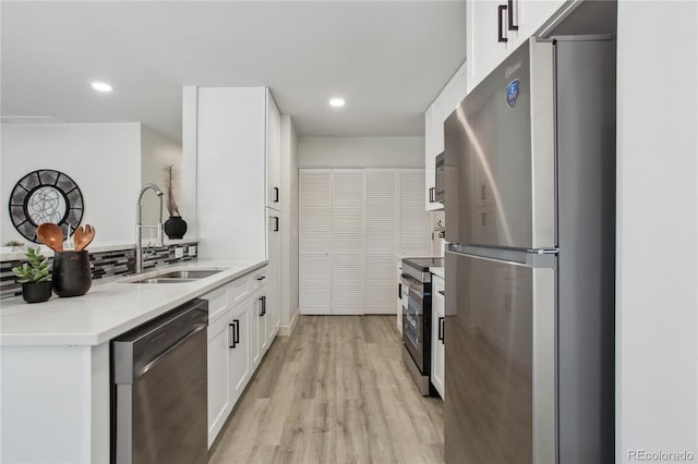7970 Chase Cir Unit 85, Arvada, CO 80003 - kitchen featuring appliances with stainless steel finishes, white cabinetry, recessed lighting, light wood finished floors, and a peninsula