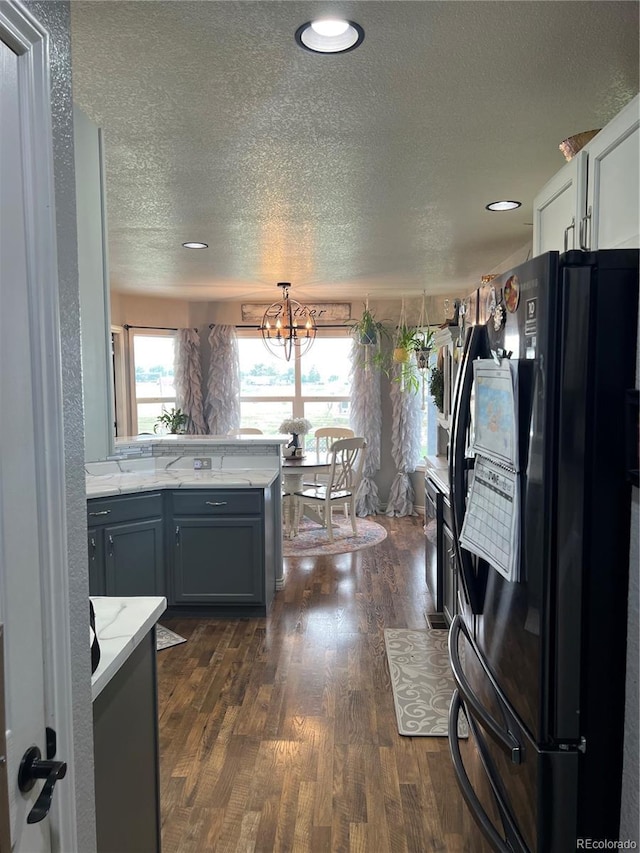 825 Cherokee St, Strasburg, CO 80136 - kitchen with freestanding refrigerator, dark wood-type flooring, a textured ceiling, a chandelier, and light stone countertops