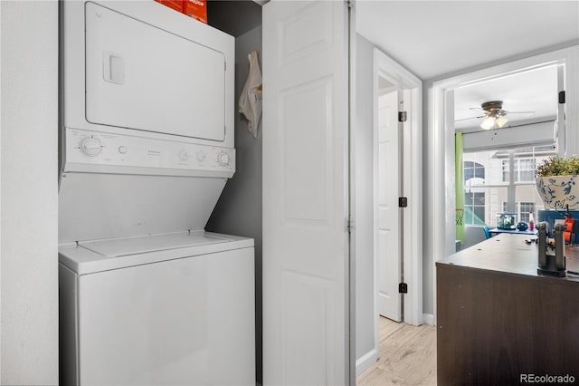 clothes washing area featuring stacked washer and clothes dryer, ceiling fan, and light hardwood / wood-style flooring