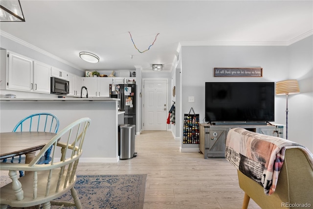 interior space featuring crown molding, white cabinets, light hardwood / wood-style flooring, and black refrigerator