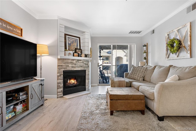 living room with light wood-type flooring, ornamental molding, and a stone fireplace