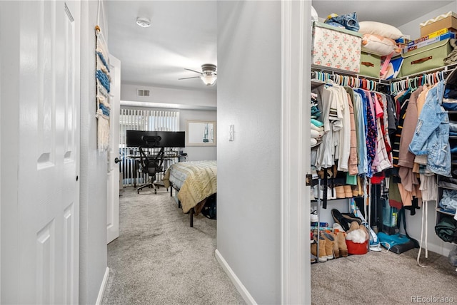 spacious closet featuring ceiling fan and light carpet