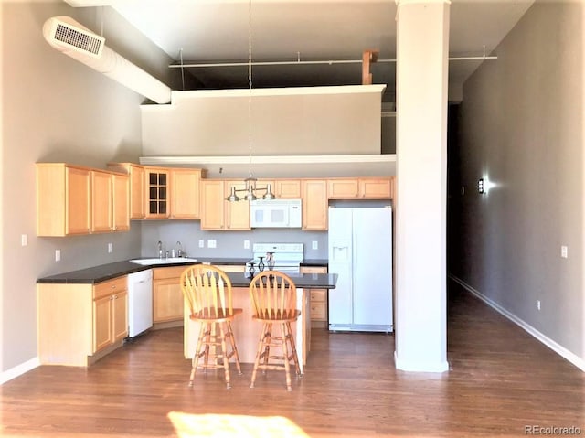 1555 California St Unit 302, Denver, CO 80202 - kitchen featuring white appliances, light brown cabinetry, dark wood-style flooring, a towering ceiling, and a kitchen island