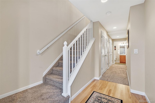 staircase featuring baseboards, wood finished floors, and recessed lighting