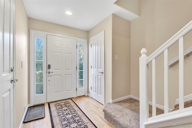 foyer entrance featuring baseboards, visible vents, stairway, and wood finished floors