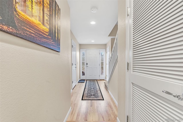 doorway featuring a textured wall, light wood finished floors, recessed lighting, and baseboards