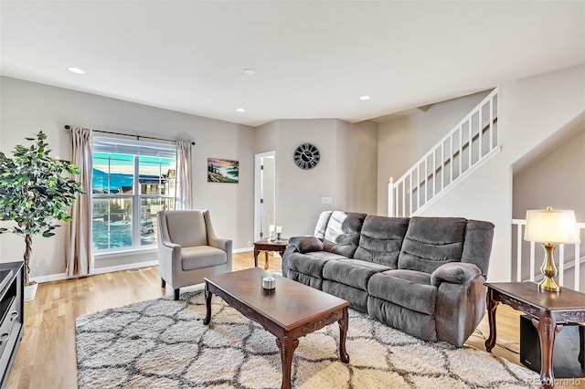 living room featuring baseboards, stairway, light wood-type flooring, and recessed lighting