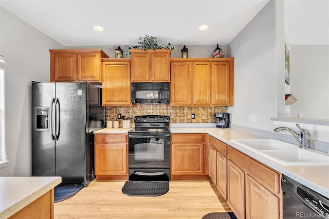 kitchen featuring black appliances, a sink, light countertops, and decorative backsplash