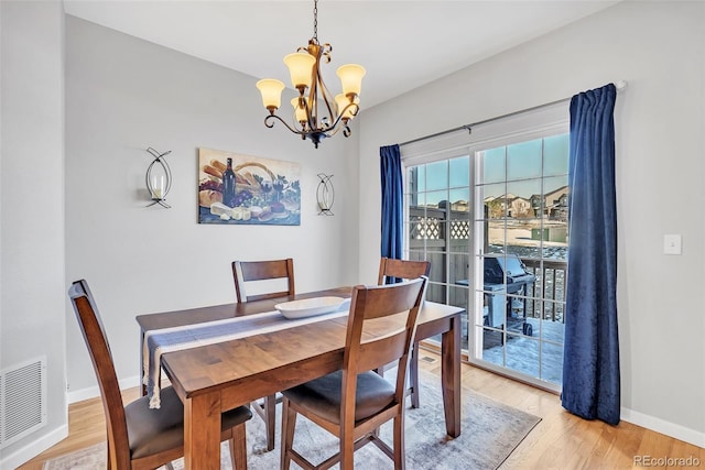 dining space with light wood-style floors, visible vents, a notable chandelier, and baseboards