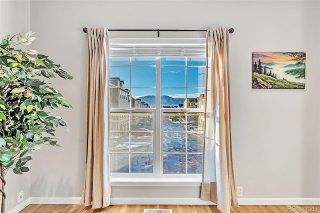 doorway to outside with wood finished floors, visible vents, and baseboards