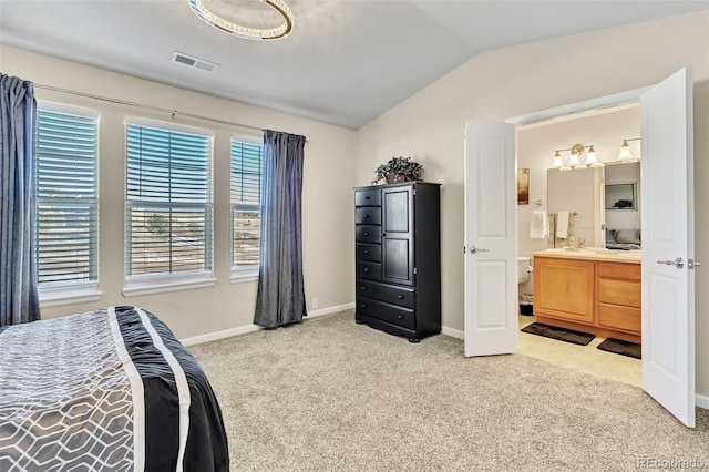 bedroom featuring light colored carpet, visible vents, vaulted ceiling, ensuite bath, and baseboards