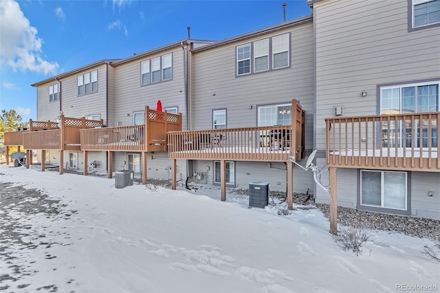 snow covered back of property featuring central air condition unit and a wooden deck