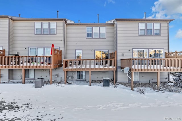 snow covered rear of property featuring central AC and a deck