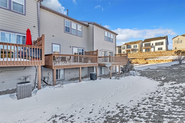 snow covered property with a residential view, a wooden deck, and central AC unit