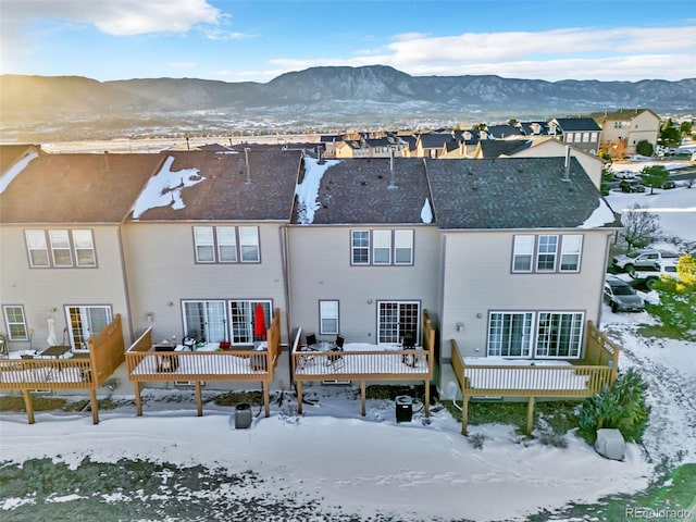 snow covered back of property featuring a residential view and a deck with mountain view