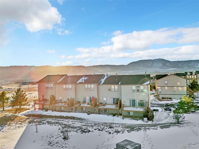 snow covered back of property with a residential view and a mountain view