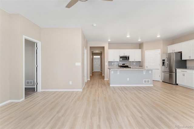 15525 Quince Cir, Thornton, CO 80602 - kitchen featuring appliances with stainless steel finishes, ceiling fan, decorative backsplash, white cabinets, and light wood-style flooring