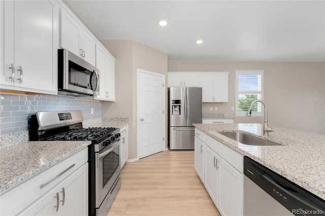 15525 Quince Cir, Thornton, CO 80602 - kitchen with stainless steel appliances, a sink, white cabinets, light wood-type flooring, and decorative backsplash