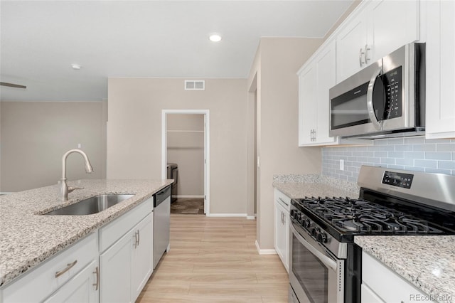 15525 Quince Cir, Thornton, CO 80602 - kitchen featuring stainless steel appliances, a sink, backsplash, white cabinetry, and light wood-type flooring