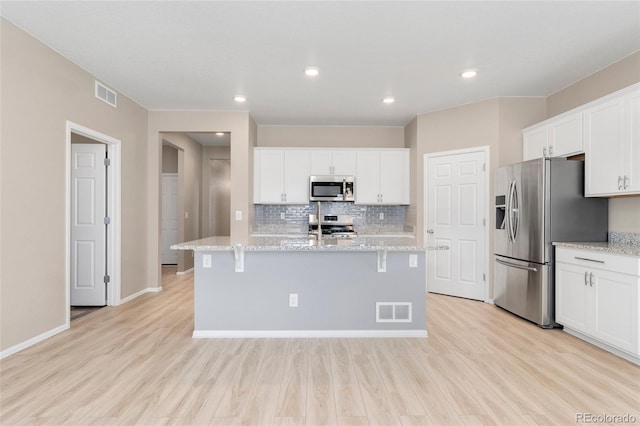 15525 Quince Cir, Thornton, CO 80602 - kitchen with appliances with stainless steel finishes, light wood finished floors, white cabinetry, decorative backsplash, and recessed lighting