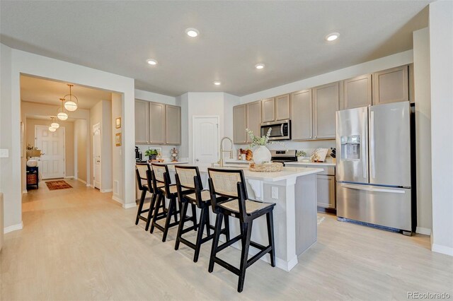 10499 Rolling Peaks Dr, Peyton, CO 80831 - kitchen featuring stainless steel appliances, a kitchen bar, light wood-style flooring, an island with sink, and recessed lighting
