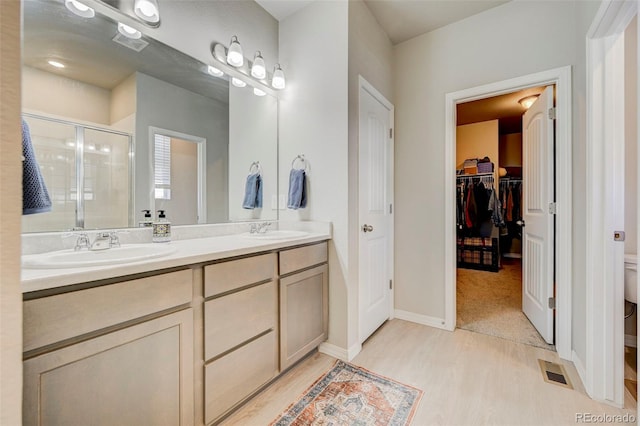 10499 Rolling Peaks Dr, Peyton, CO 80831 - full bath featuring wood finished floors, a stall shower, double vanity, toilet, and baseboards