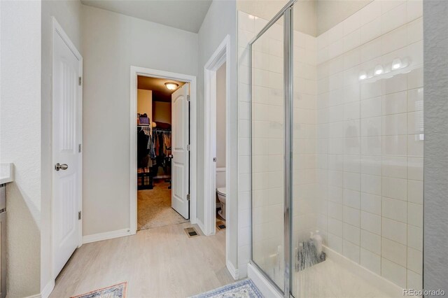10499 Rolling Peaks Dr, Peyton, CO 80831 - full bath with a stall shower, wood finished floors, toilet, a walk in closet, and baseboards