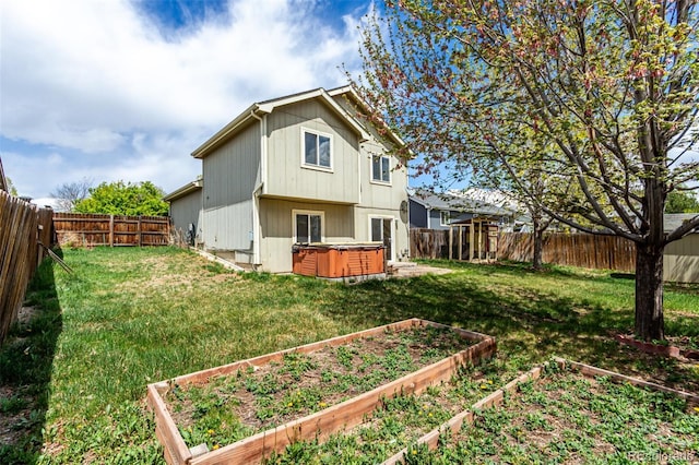 4318 Suncreek Dr, Loveland, CO 80538 - rear view of property with a fenced backyard, a lawn, a hot tub, and a vegetable garden