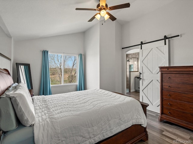 6055 W Progress Ave, Littleton, CO 80123 - bedroom with lofted ceiling, a barn door, wood finished floors, and ceiling fan