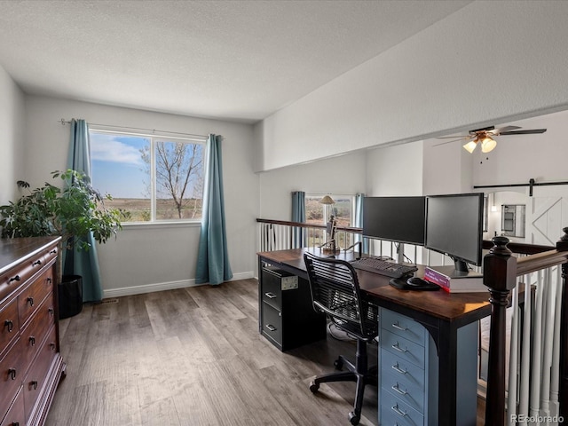 6055 W Progress Ave, Littleton, CO 80123 - office with light wood-style floors, a ceiling fan, a textured ceiling, and a barn door