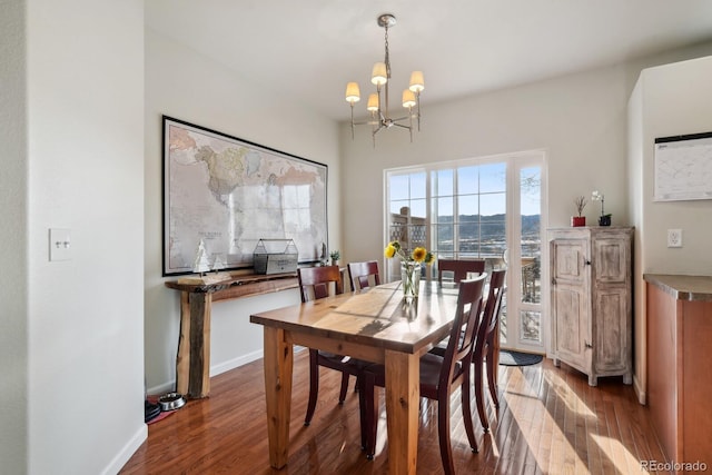 dining space with dark hardwood / wood-style floors and a notable chandelier