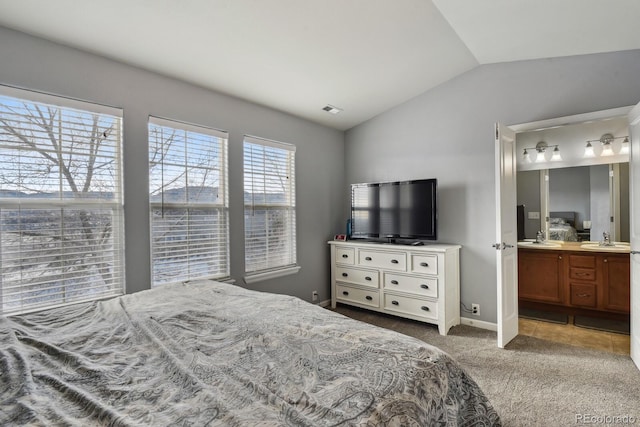 bedroom with ensuite bath, light carpet, sink, and lofted ceiling