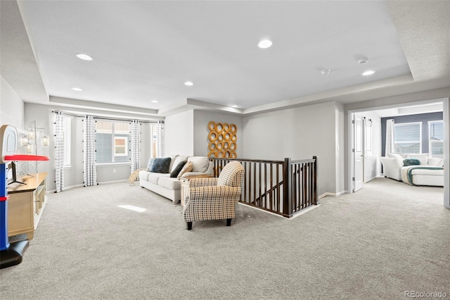 living room featuring carpet floors and a tray ceiling