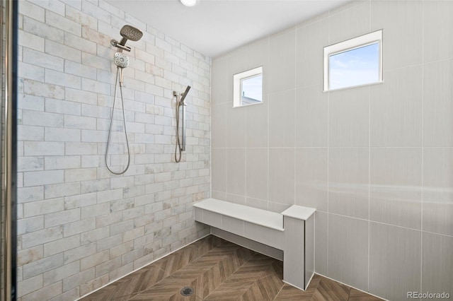 bathroom with parquet flooring, plenty of natural light, and tiled shower