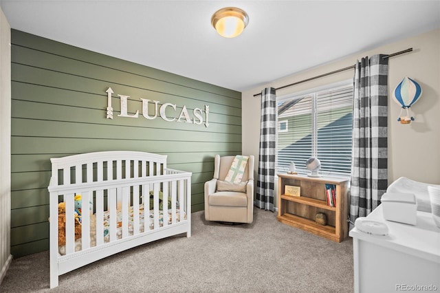 carpeted bedroom featuring a nursery area and wooden walls