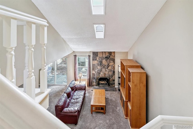 carpeted living room featuring lofted ceiling, a fireplace, and a textured ceiling