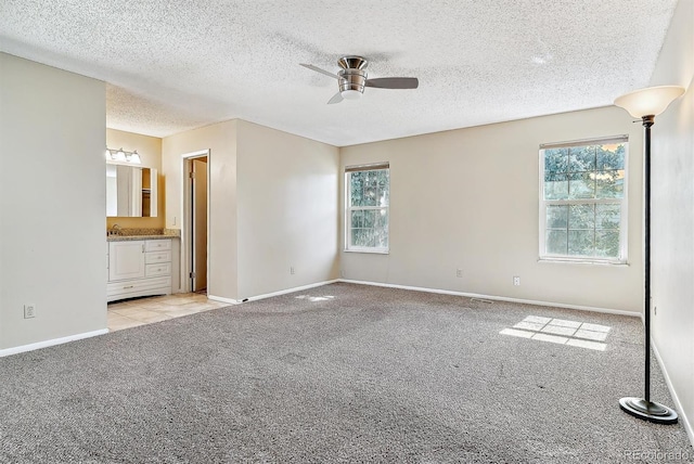 interior space with light carpet, a healthy amount of sunlight, ceiling fan, and a textured ceiling